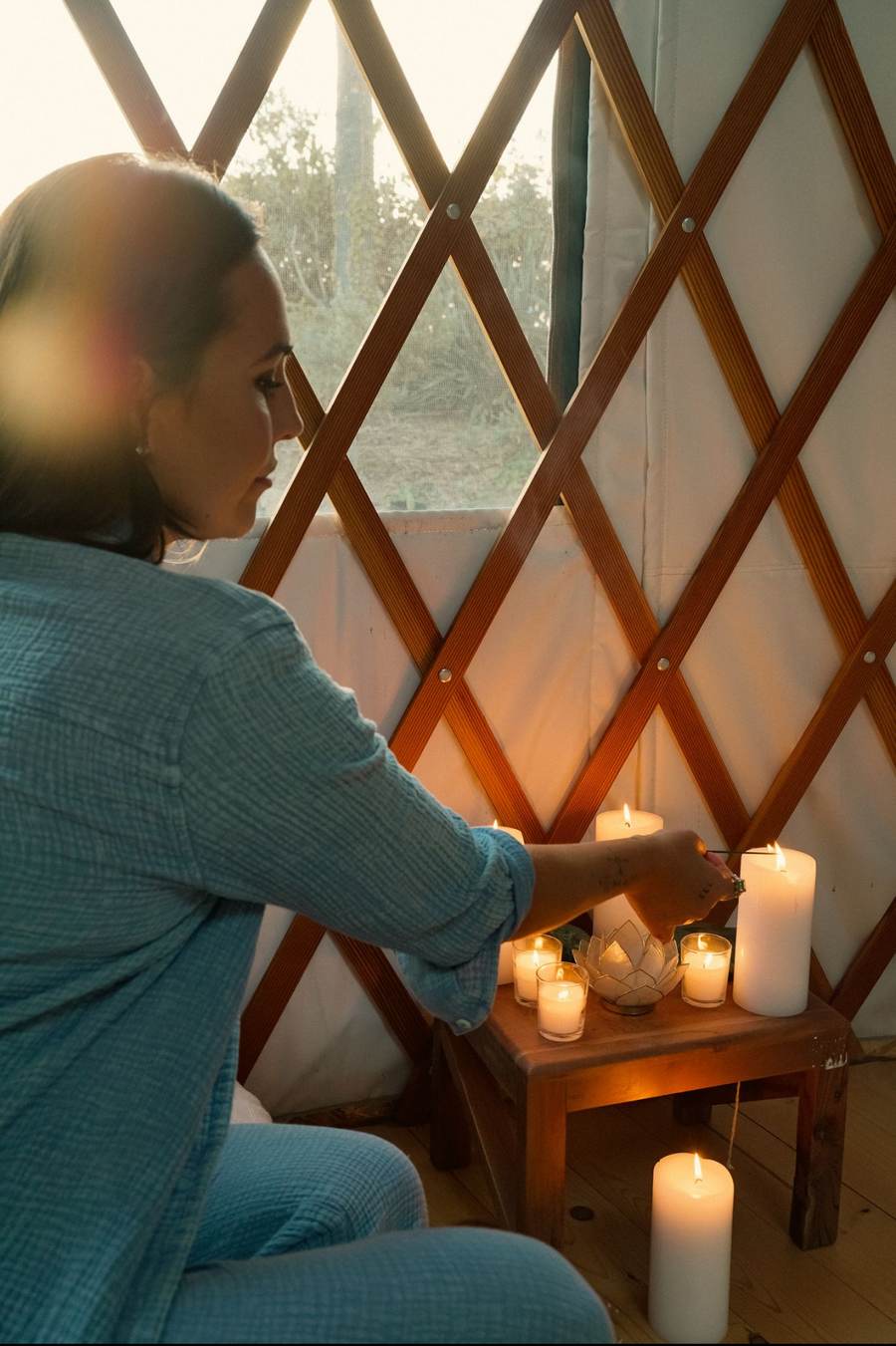 Sasha lighting candles by the yurt lattice at golden hour